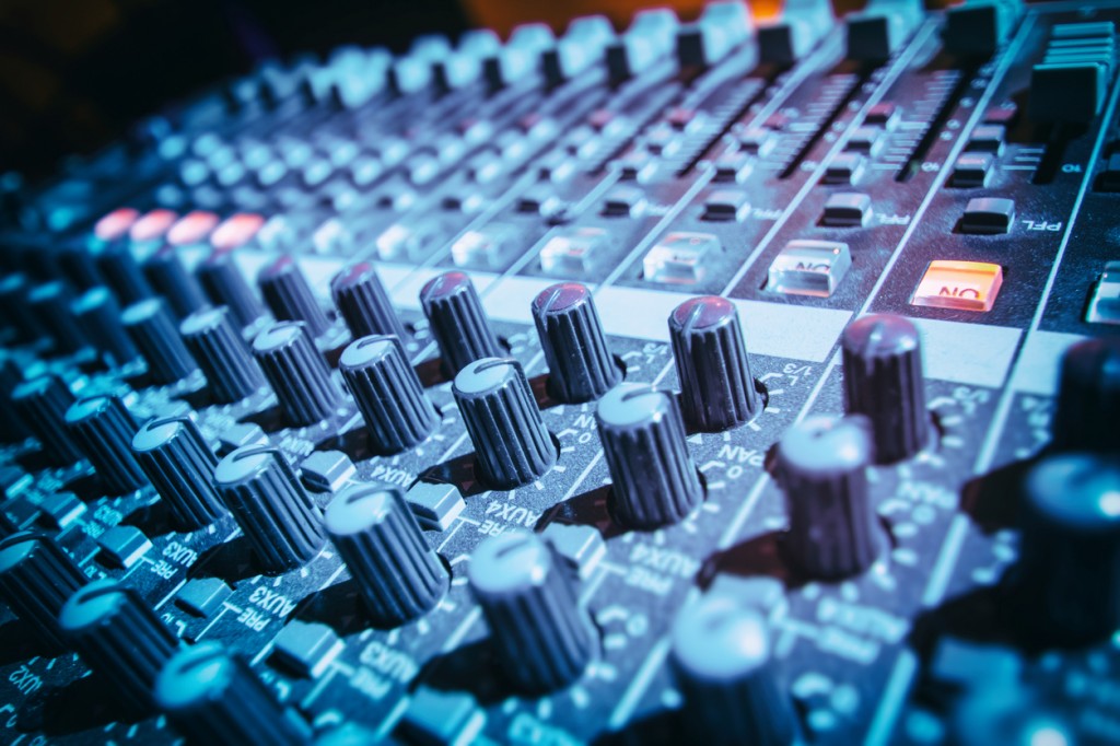 Close-up of DJ's sound mixing desk illuminated by blue light